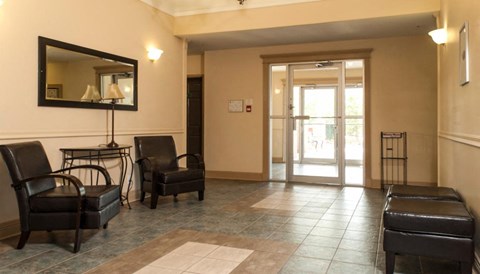 the lobby of a building with chairs and a mirror