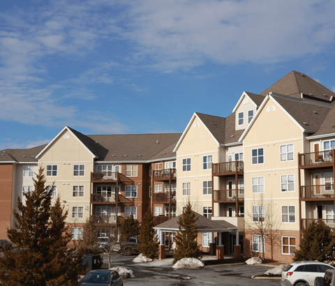 A large apartment complex with a parking lot in front.