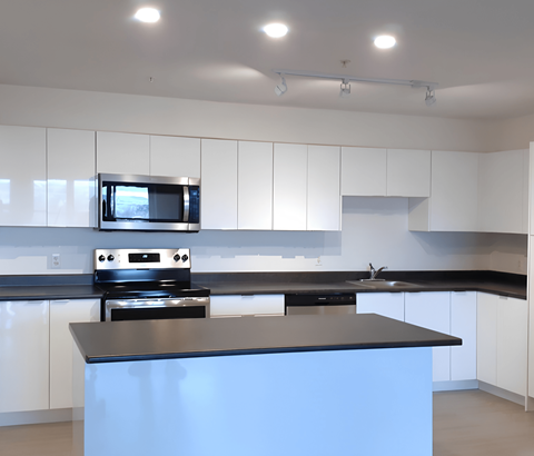 A kitchen with a black countertop and white cabinets.