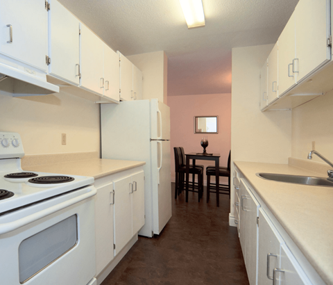 A kitchen with white appliances and cabinets.