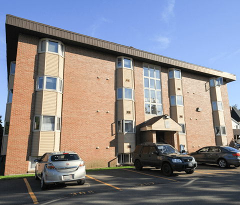 A car is parked in front of a brick building.
