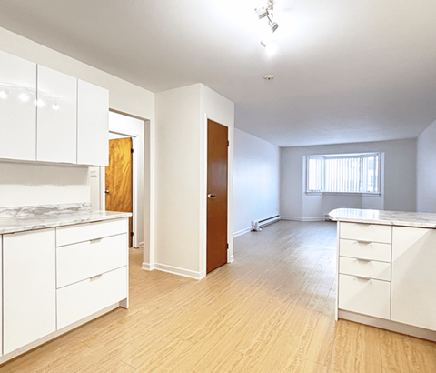A kitchen with white cabinets and a wooden door.