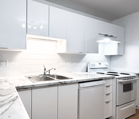 A white kitchen with a sink and stove.