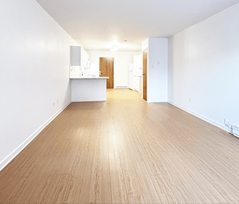 A spacious room with wooden flooring and white walls.