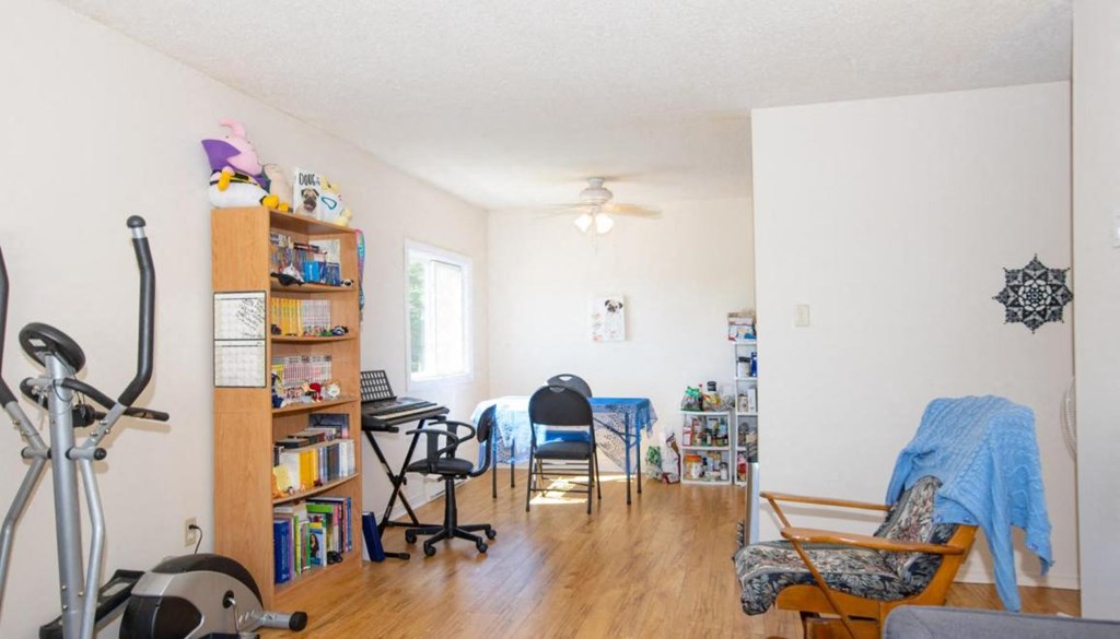 A living room with a bookshelf, exercise equipment, and a blue blanket on a chair.