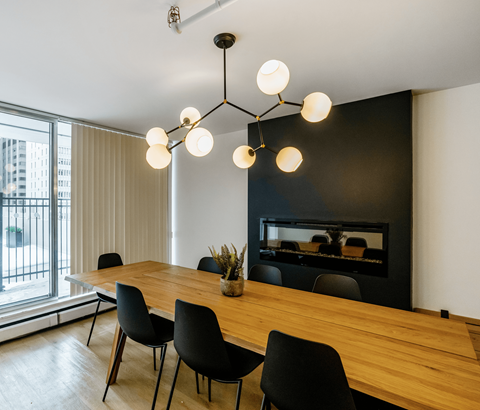 A modern dining room with a wooden table and black chairs.