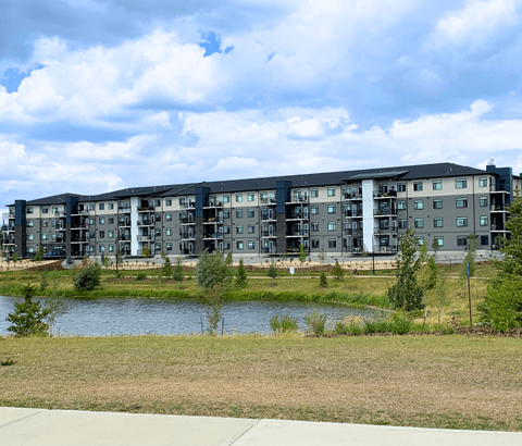 A modern apartment complex with a lake in front.