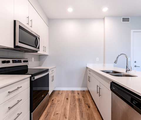 A kitchen with white cabinets and black appliances.