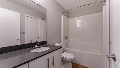 A white toilet sits in a bathroom next to a sink and a bathtub.