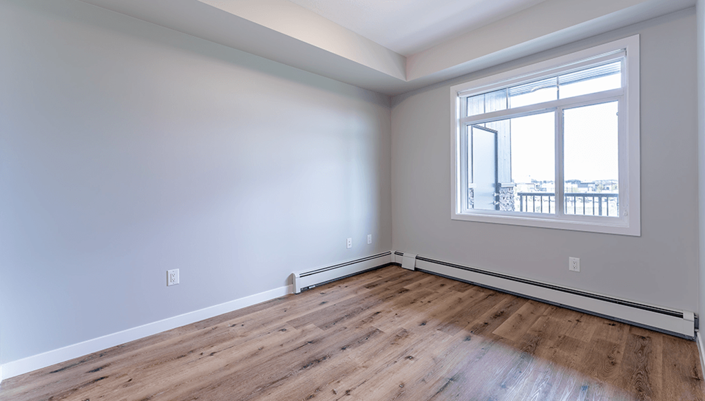 A room with a window and wooden flooring.