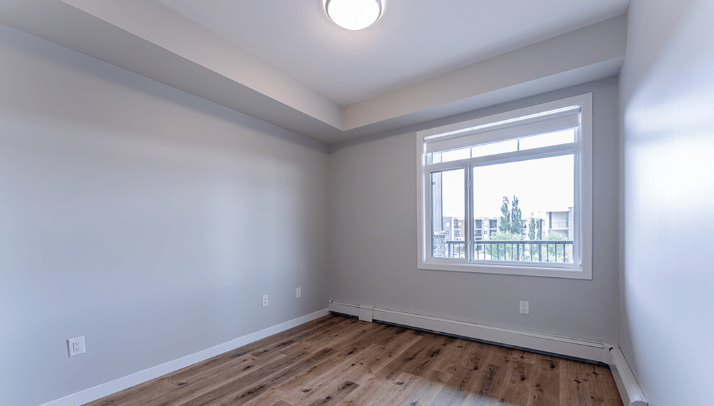 A room with a window and wooden flooring.
