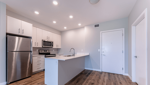 A modern kitchen with a stainless steel refrigerator and white cabinets.