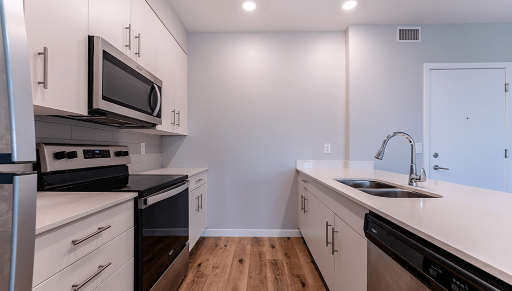 A kitchen with white cabinets and black appliances.
