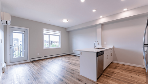 A kitchen with a white counter and wooden floors.