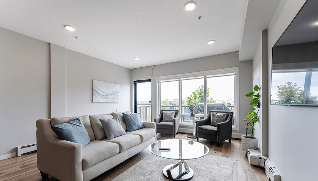 A modern living room with a grey sofa and a glass table.