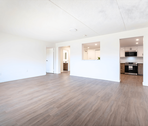 A spacious room with wooden flooring and white walls.