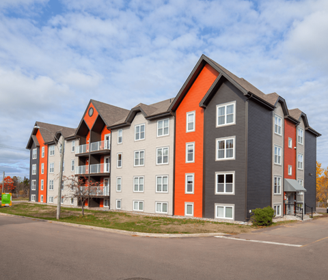 A large apartment building with grey and orange accents.