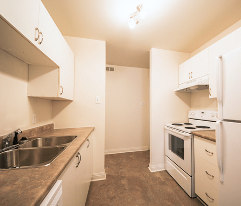 A kitchen with white appliances and a brown counter top.