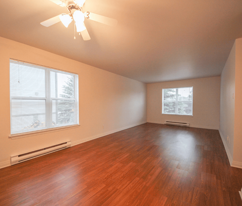 A room with a ceiling fan and wooden flooring.
