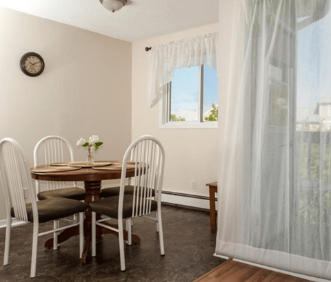 A dining room with a table and chairs.