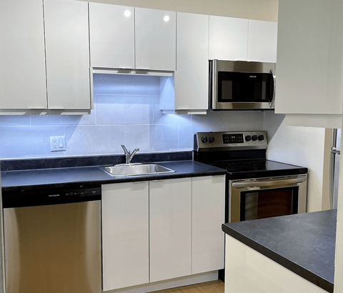 A modern kitchen with white cabinets and black countertops.