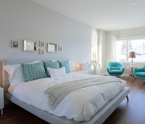 A bedroom with a large bed and a blue chair.