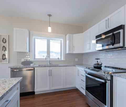 A kitchen with white cabinets and a stainless steel dishwasher.