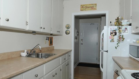 A kitchen with a refrigerator covered in magnets and a sign that says "Sweet".