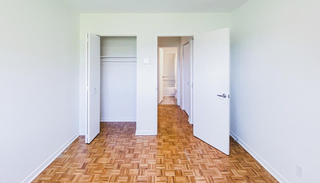 A hallway with a wooden floor and white walls.