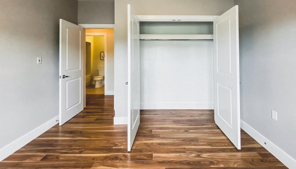 A room with a white door and a wooden floor.