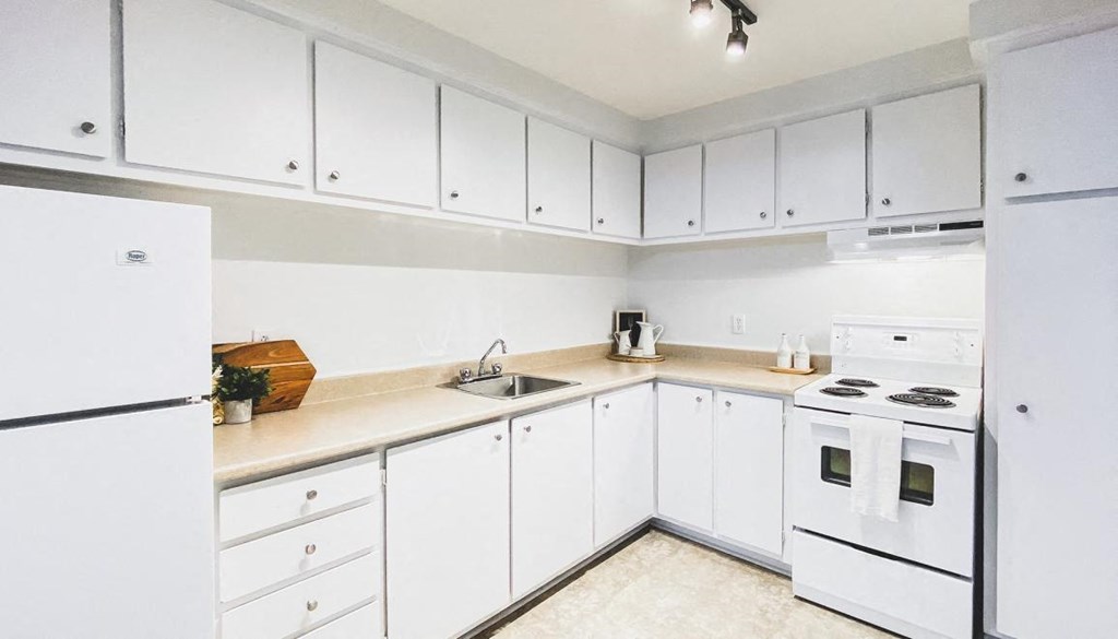 A kitchen with white appliances and cabinets.