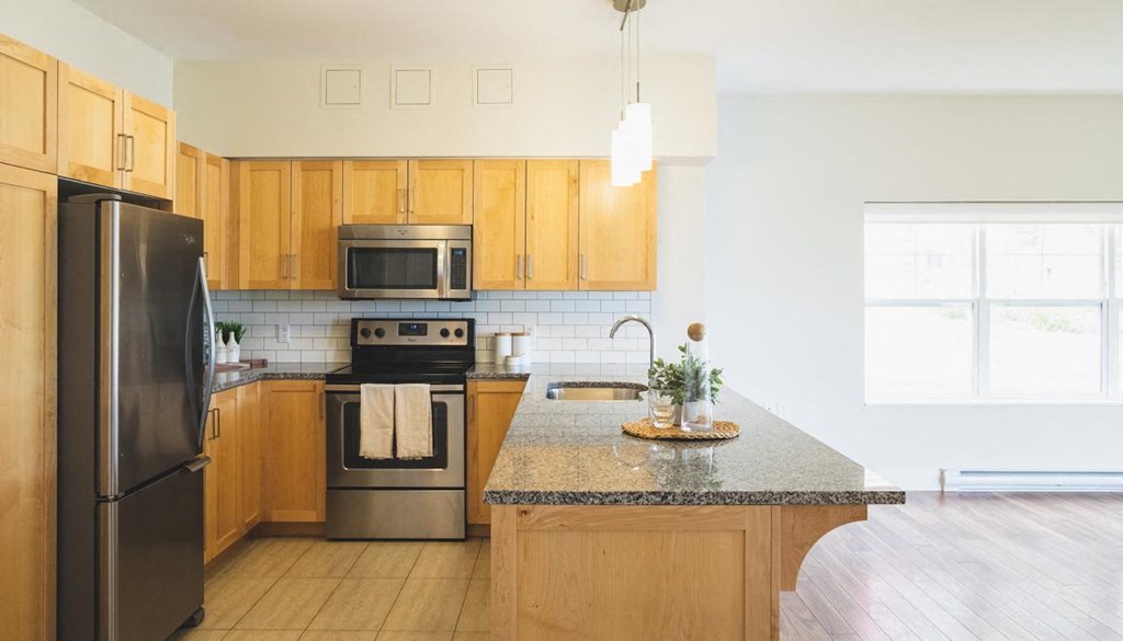 A kitchen with wooden cabinets and a black refrigerator.
