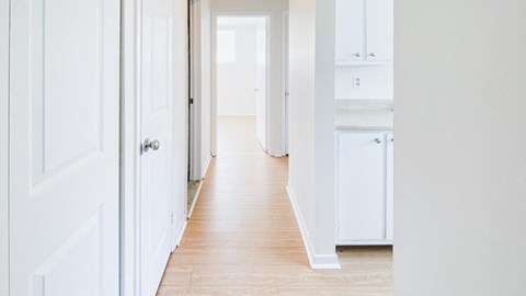 A long hallway with white doors and drawers.