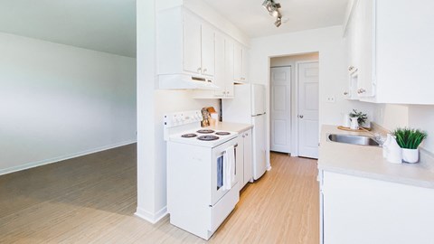 A white kitchen with wooden floors and white cabinets.