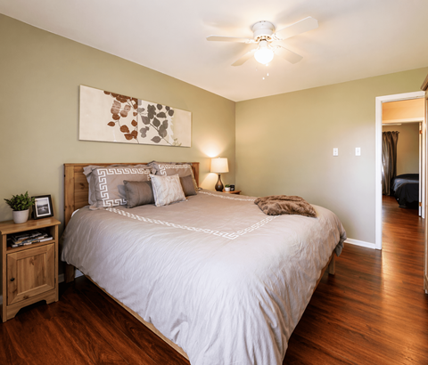 A bedroom with a large bed and a ceiling fan.