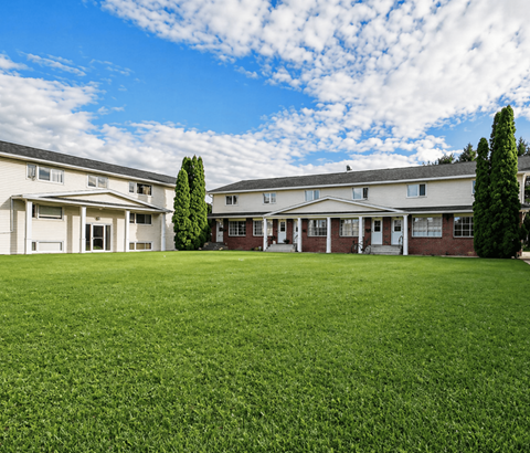 A row of houses with a green lawn in front.