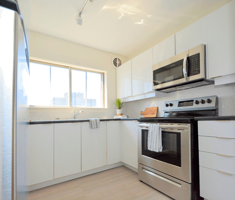 A modern kitchen with a stainless steel oven and white cabinets.