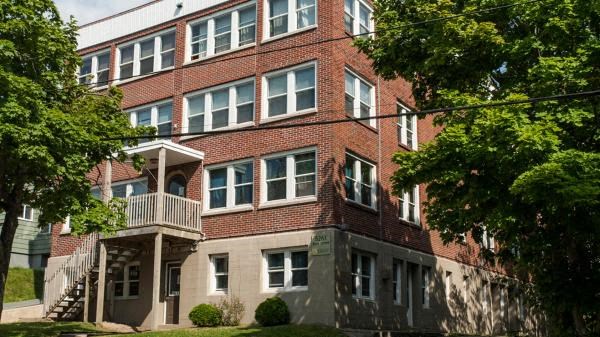 a red brick apartment building with a balcony and trees