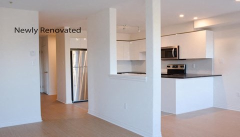 an empty kitchen with white cabinets and a black counter top