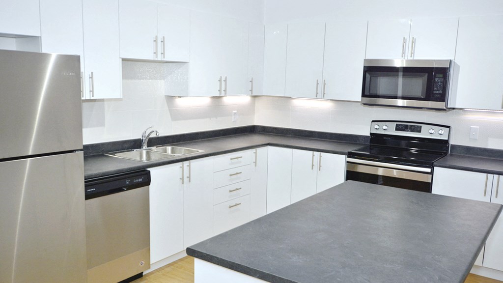 an empty kitchen with white cabinets and stainless steel appliances