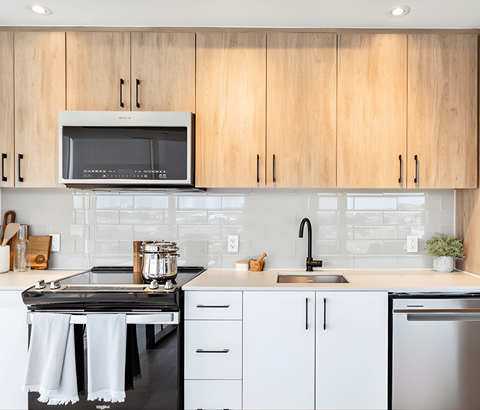 A modern kitchen with wooden cabinets and a black stove top.