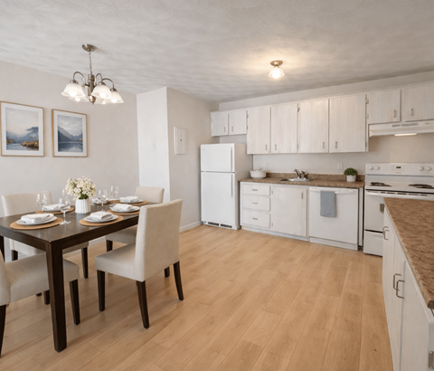A kitchen with a table set for two and a refrigerator.