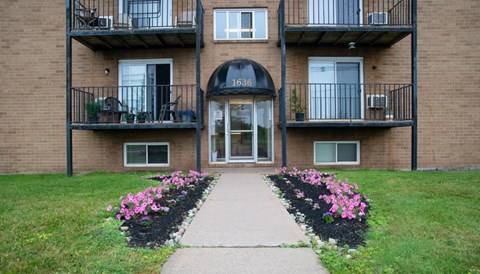 The front of apartment building 1636 with a walkway and flowers in the front.