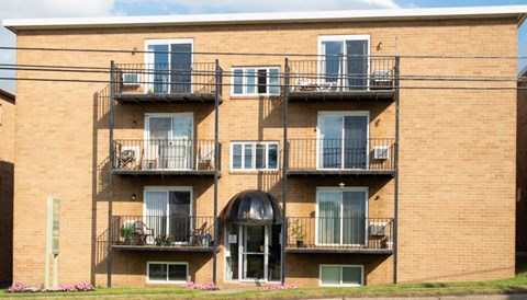 A brick building with balconies and flower pots on the ground.