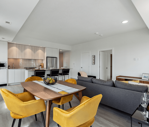 A modern kitchen with a dining table and yellow chairs.