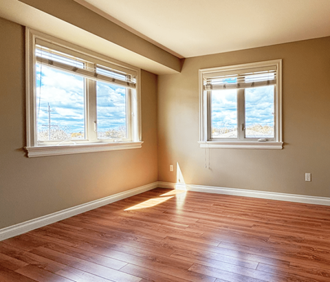 A room with wooden floors and two windows.