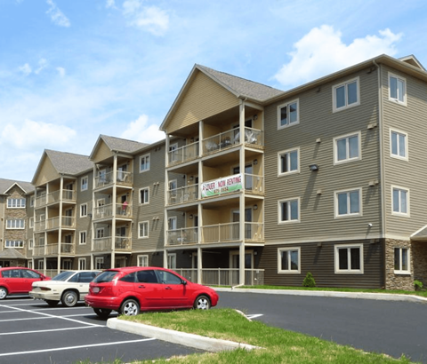 A row of apartment buildings with a red car parked in front.