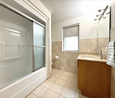 A bathroom with a sink, mirror, and shower.