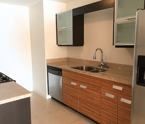 A kitchen with a sink, dishwasher, and refrigerator.