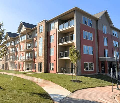 A multi-story apartment building with a walkway in front.